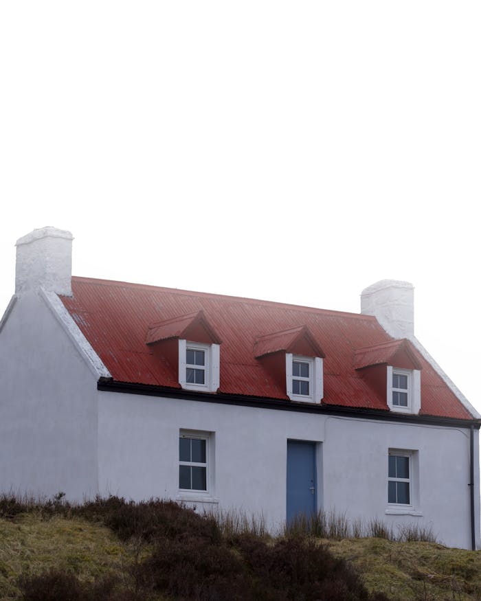 our-services-2 Charming white cottage with red roof in Scotland set against cloudy skies.