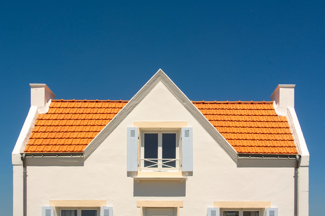 gallery-4 Front view of a house with orange tile roof and blue sky background.