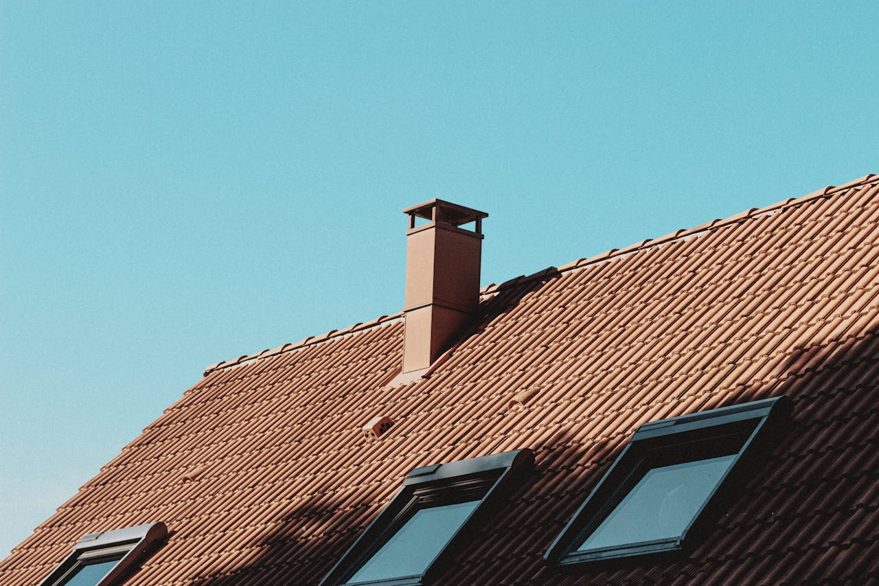 gallery-3 From below of chimney and attic windows on tiled roof of modern residential house against cloudless blue sky