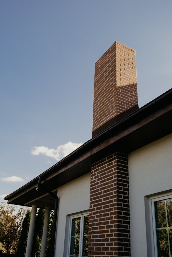 about-01 A striking modern brick chimney on a contemporary house exterior under a clear blue sky.