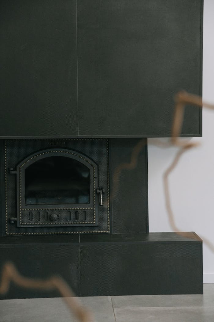 our-services-1 A sleek black fireplace with a modern design element in a minimalist interior space.